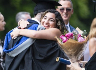 A graduand and a guest hugging