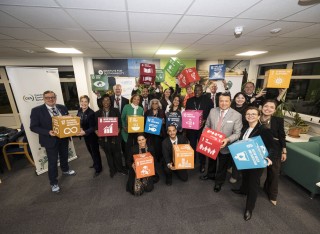 staff and academics inside a university room holding boxes of each of the UN's Sustainable Development Goals