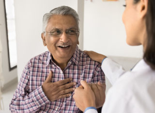 Young doctor woman calming senior Indian patient, holding mans hand, touching shoulder with comfort, support, compassion, telling good news about health, heart work