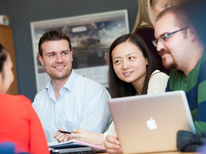 Four Surrey Executive MBA students sitting around a laptop