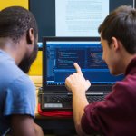 two students are looking at code on a computer