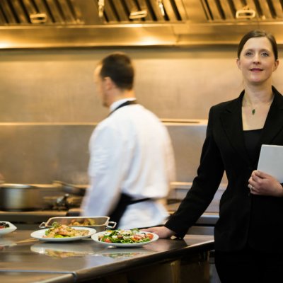 A restaurant manager stands in a busy hotel restaurant kitchen