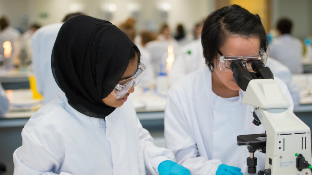 Two biosciences students looking through a microscope