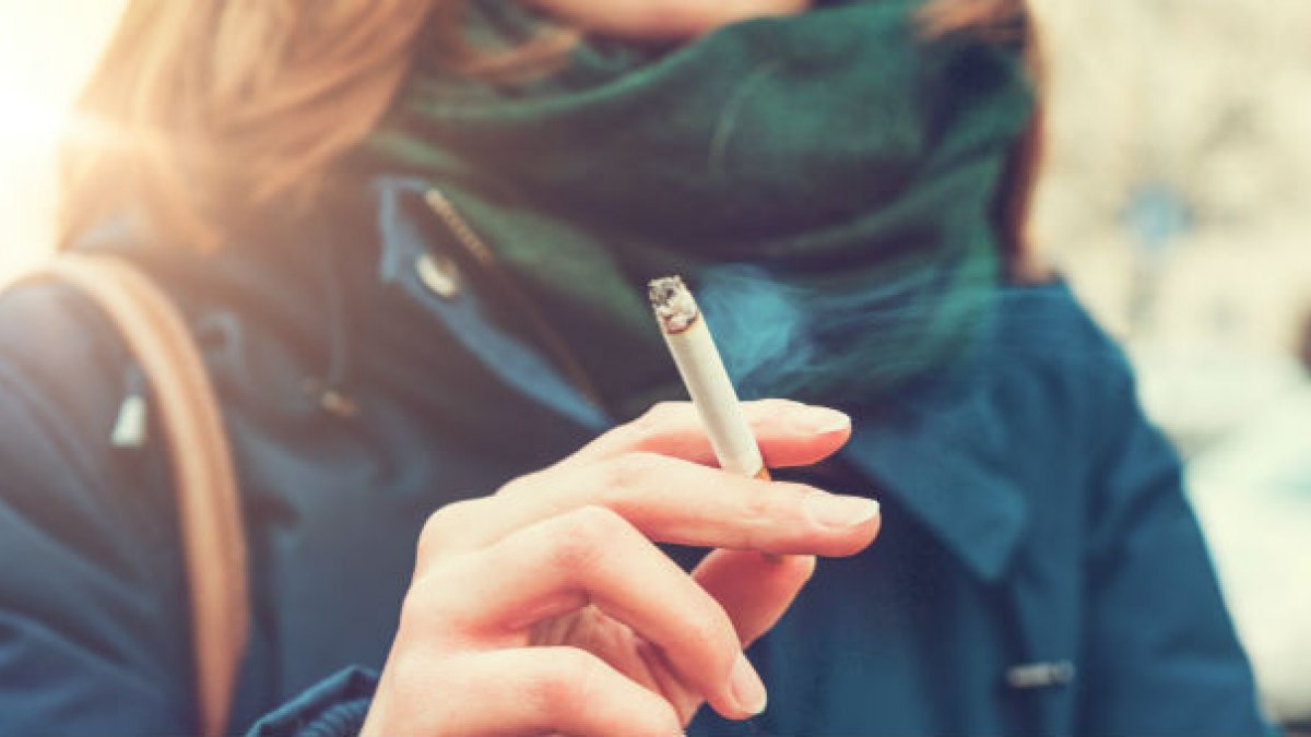 A lady holding a lit cigarette in her right hand