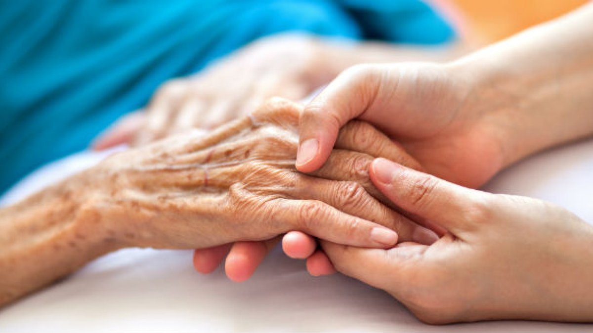 Holding the hand of an old person in a hospital bed