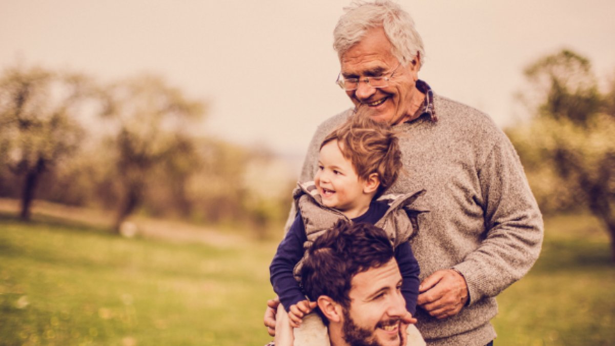 A young man with his son on his shoulders next to his older father