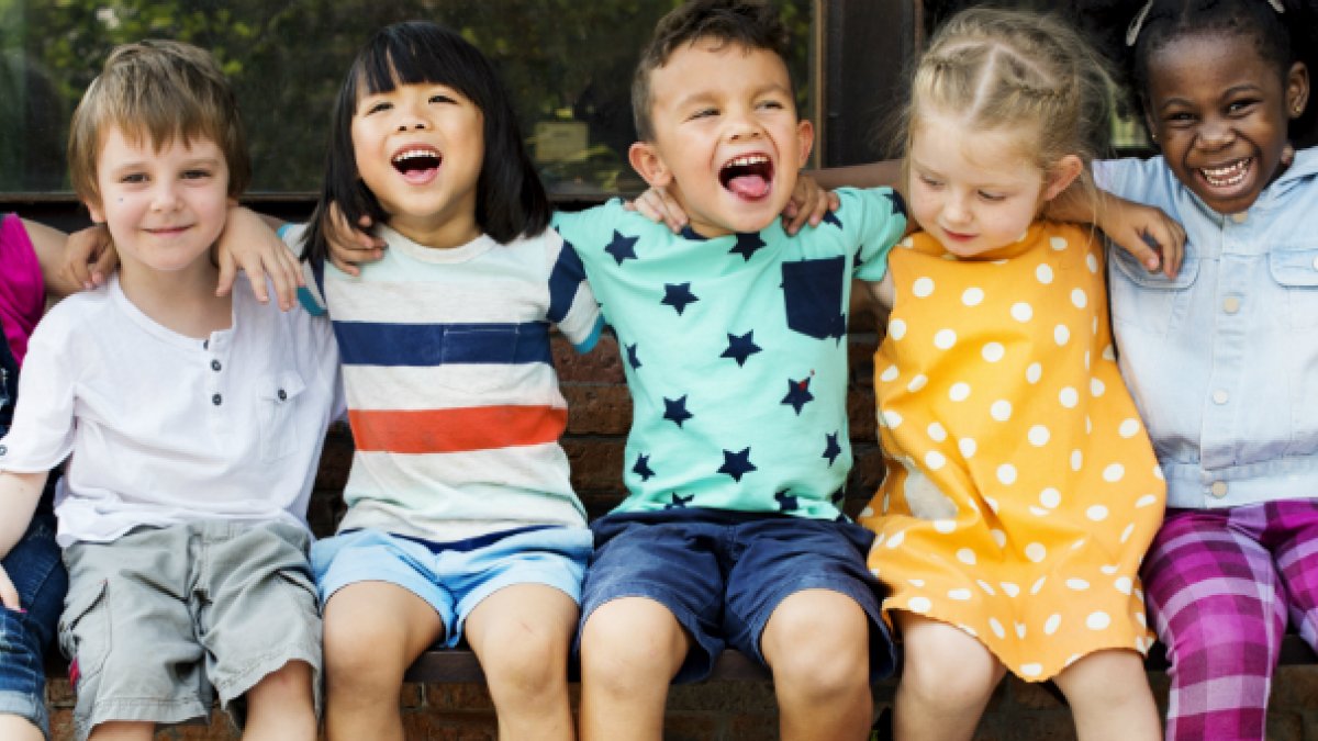 A group of children sitting in a row smiling and laughing