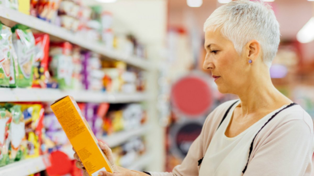 Lady reading health information on a packet of food in the supermarket