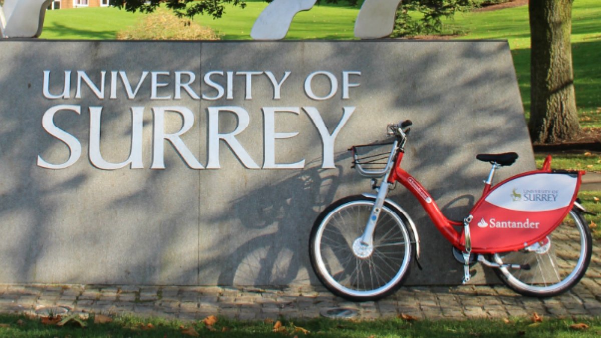 Red Santander bike in front of the University of Surrey stag statue