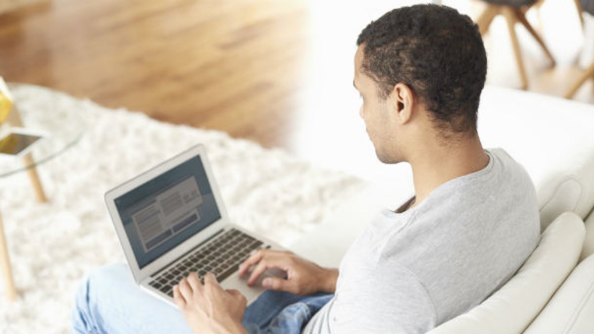 Man sitting on sofa using laptop