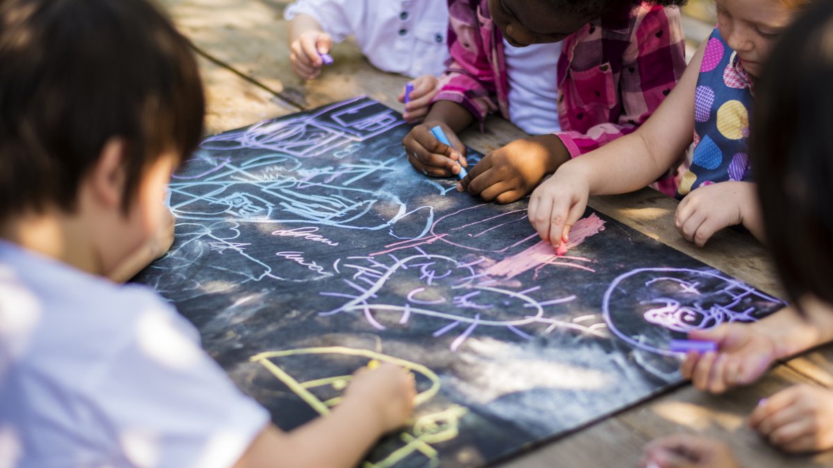 Children in a nursery drawing on the ground