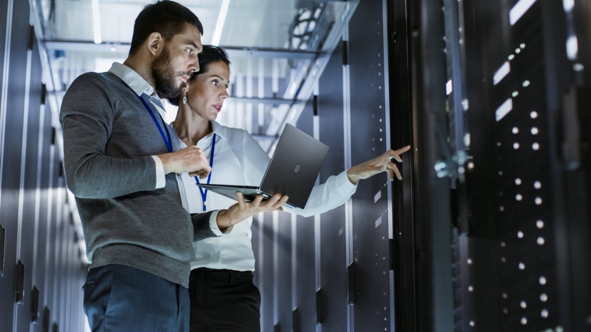 Two people standing in front of a computer server