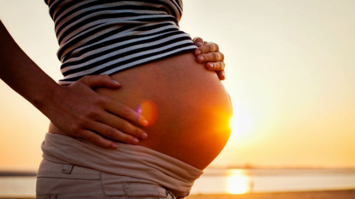 Pregnant woman standing on a beach at sunset