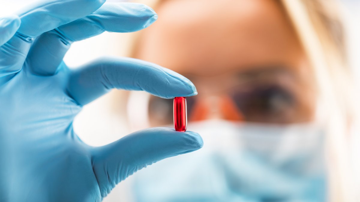 Scientist holding red pill