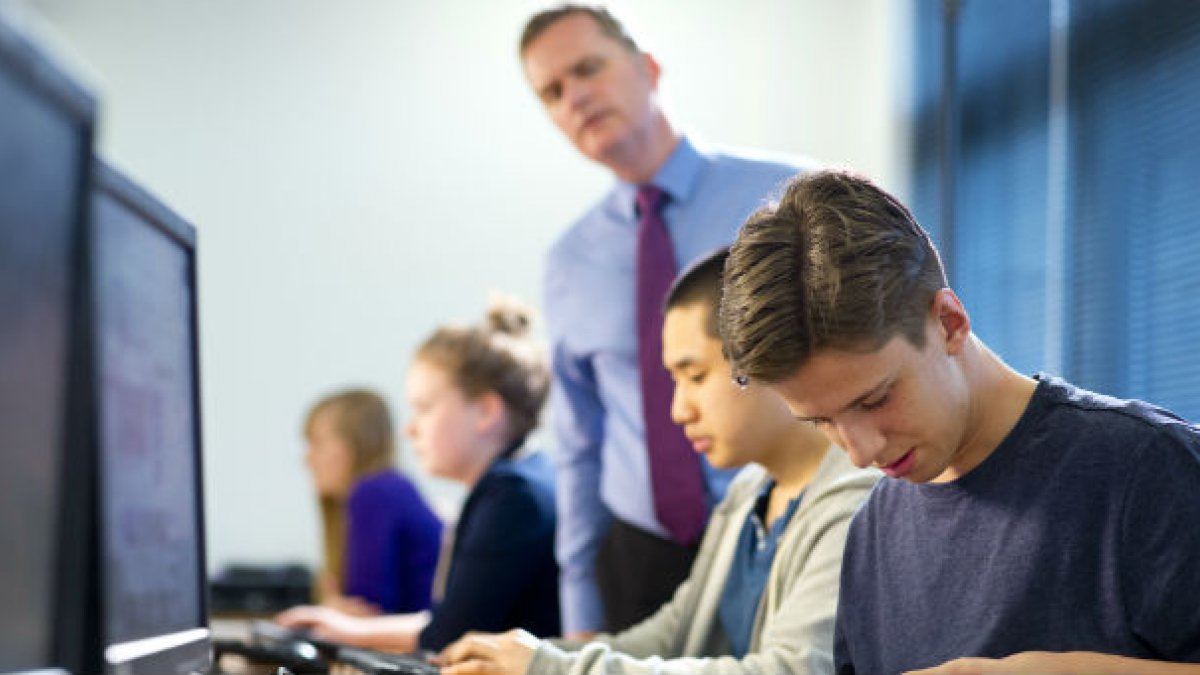 Students and teacher working in front of computers