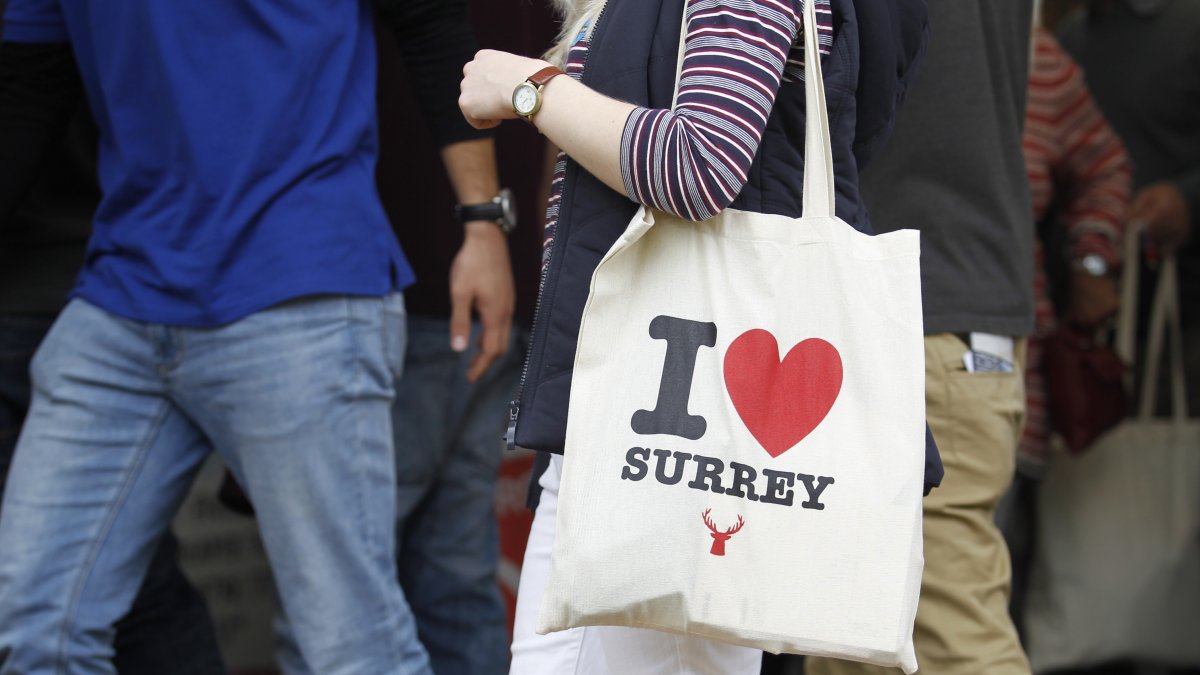 Person holding an 'I love Surrey' bag in a crowd
