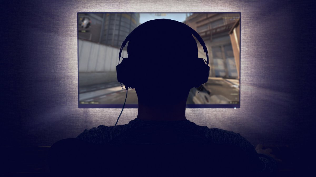 Person wearing headphones in front of a screen in a dark room