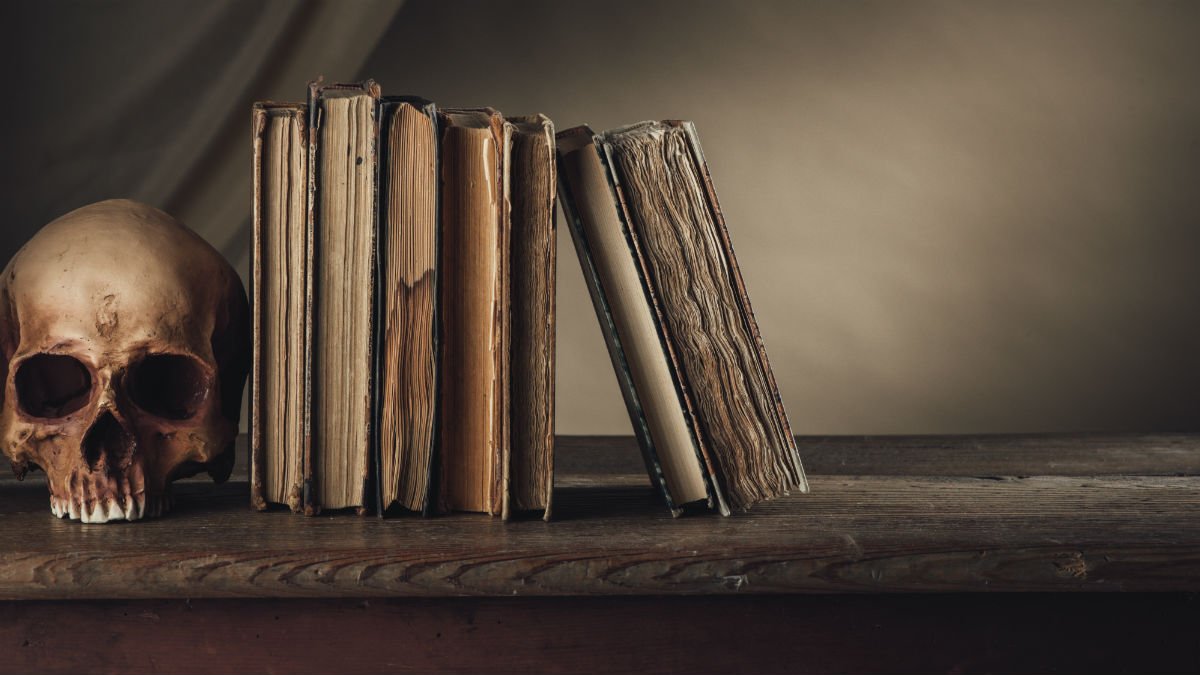Gothic literature books sit on a shelf next to a skull