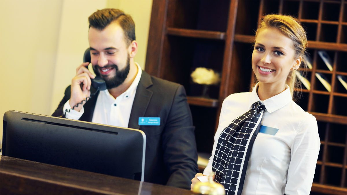A male and female reception worker working together in a hotel