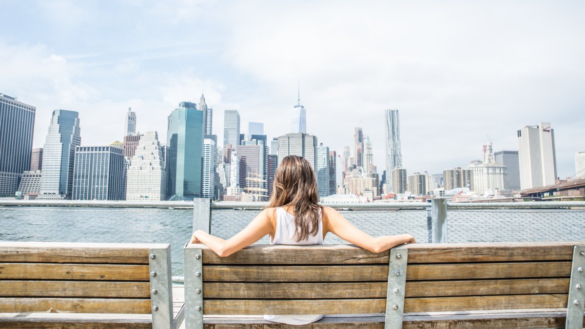 Girl sat on bench looking at cityscape