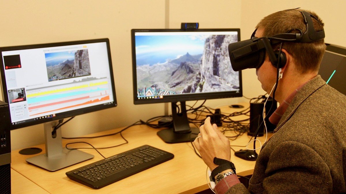 Male sitting with virtual reality type headset on looking at computer screen