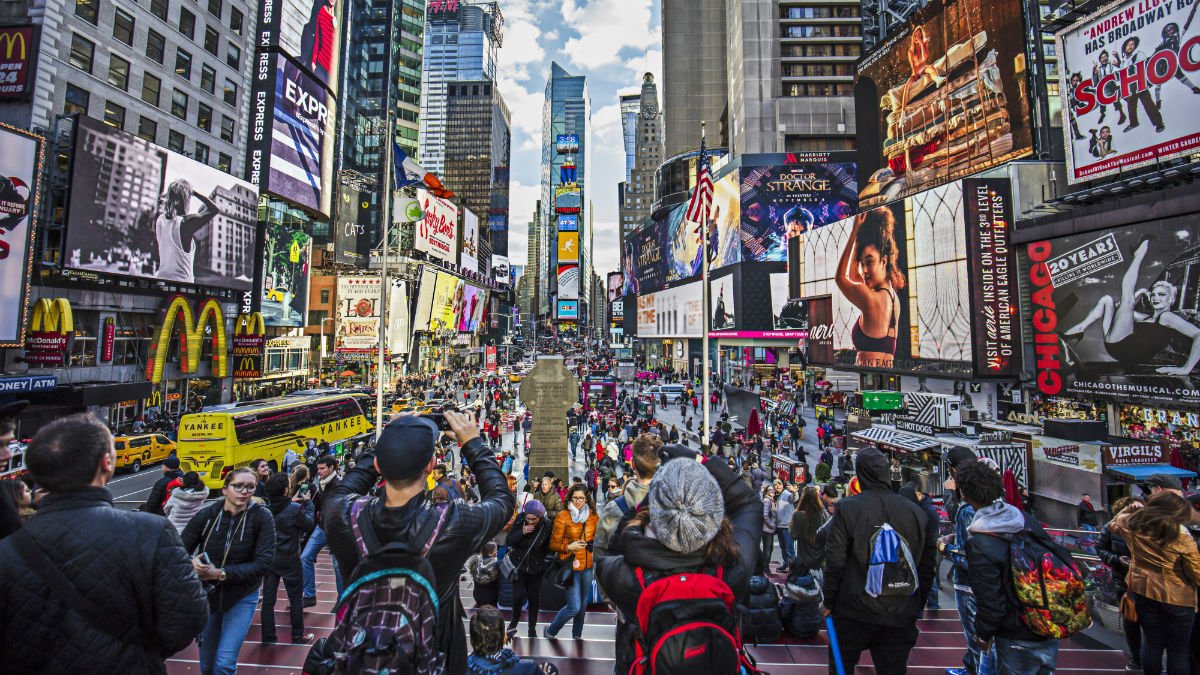 A busy scene showing tourists walking round New York
