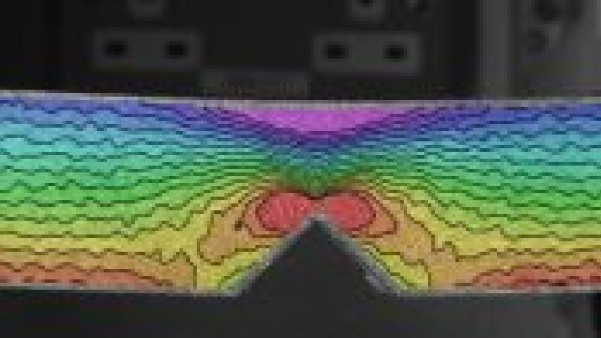 Example of output from DIC – here, a notched specimen is placed in four point bending, with the notch in the tensile face. The image shows the intensity of the tensile and compressive forces at the surfaces, decreasing to zero at the neutral axis, but concentrated at the tip of the notch.