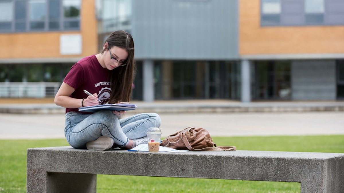 Student sitting on bench reading