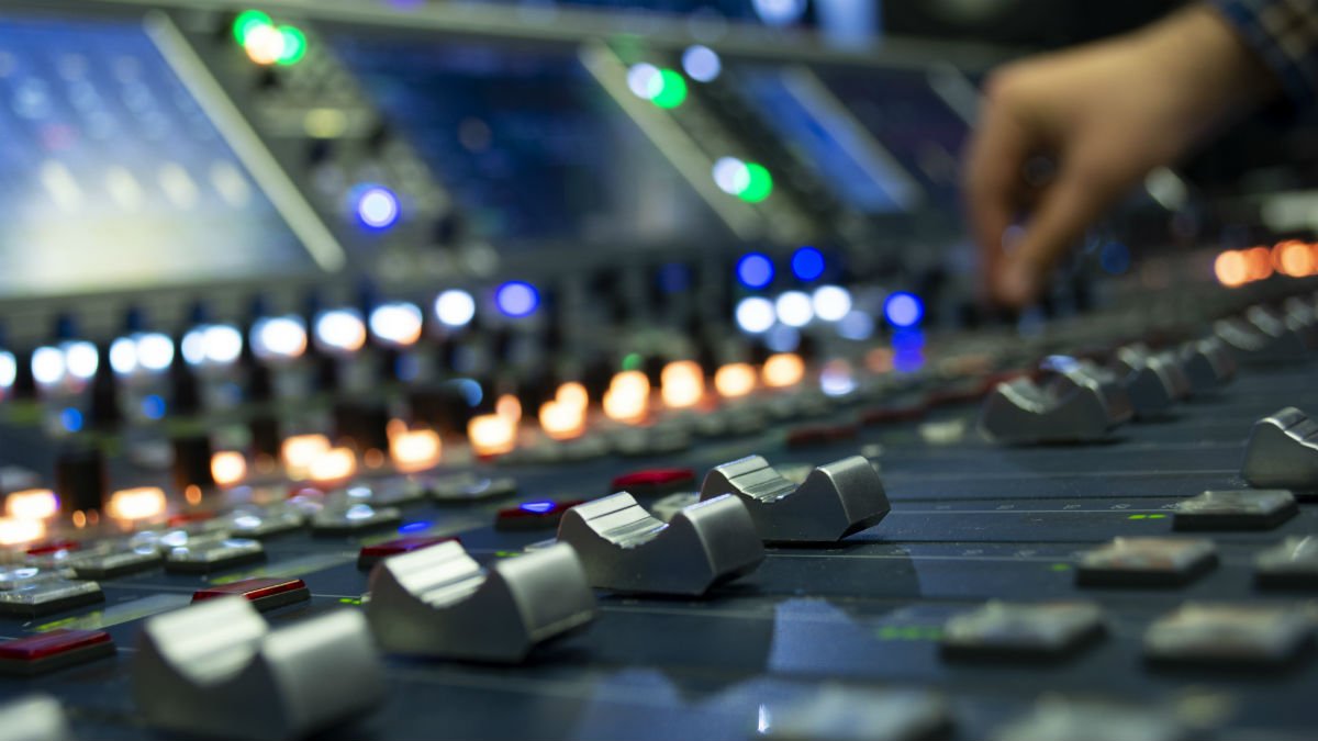 A hand navigates a sound mixing desk
