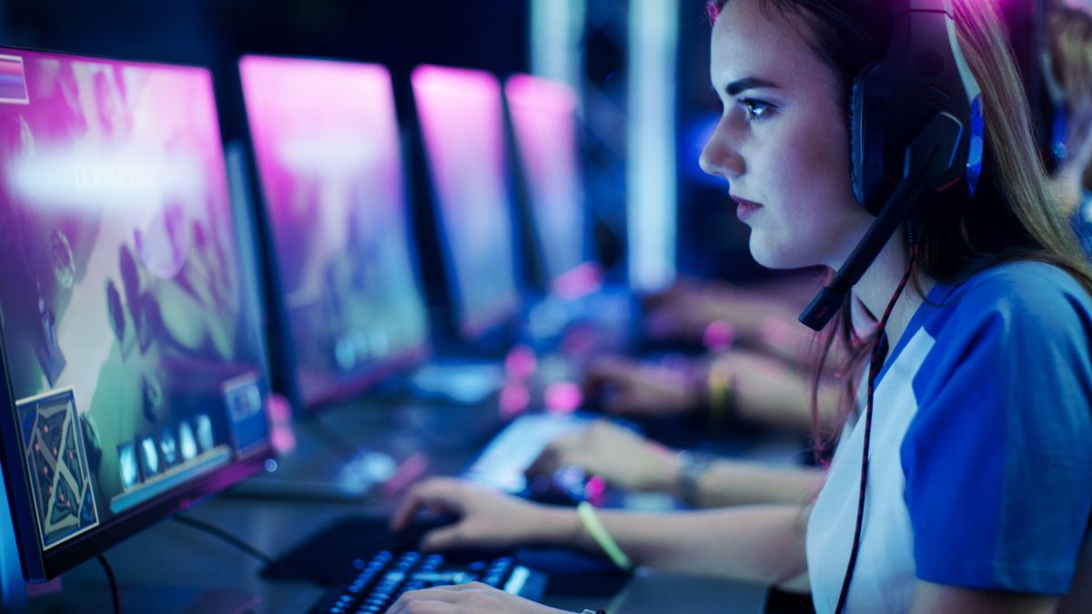 Girl playing video games on a computer wearing a headset