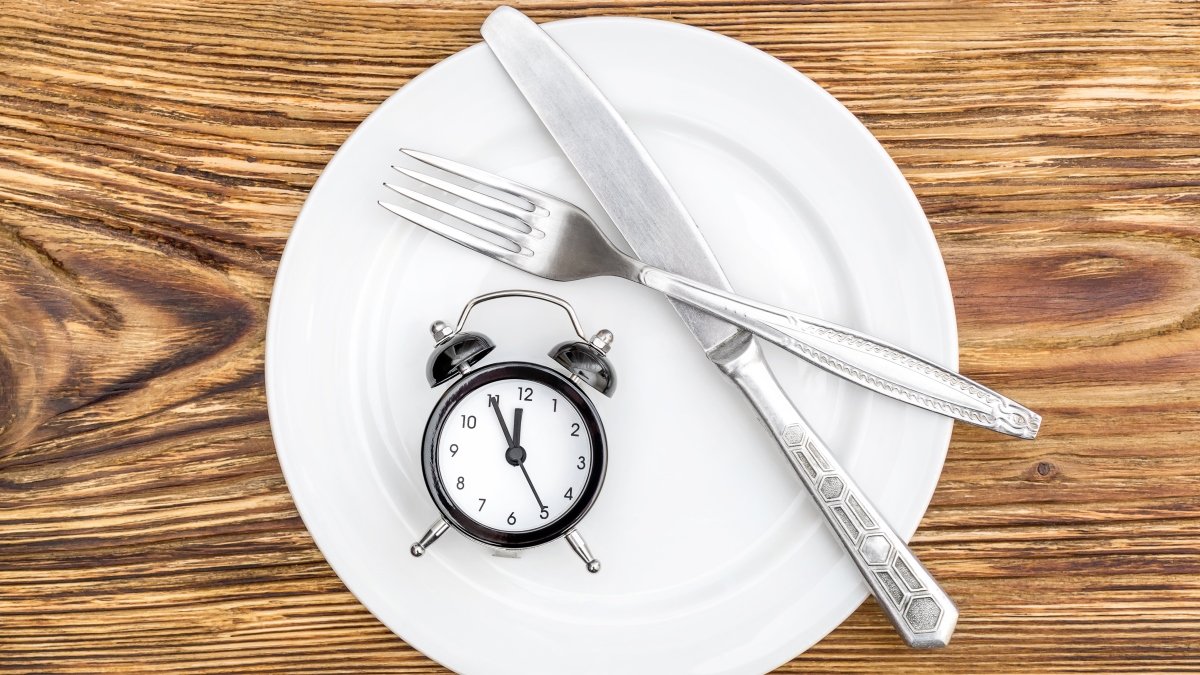 Knife and fork on plate next to alarm clock