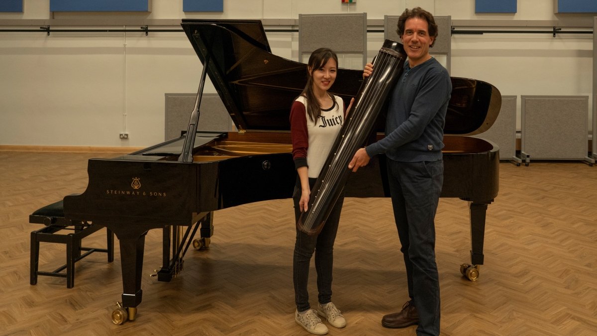 Man and woman holding the donated guqin