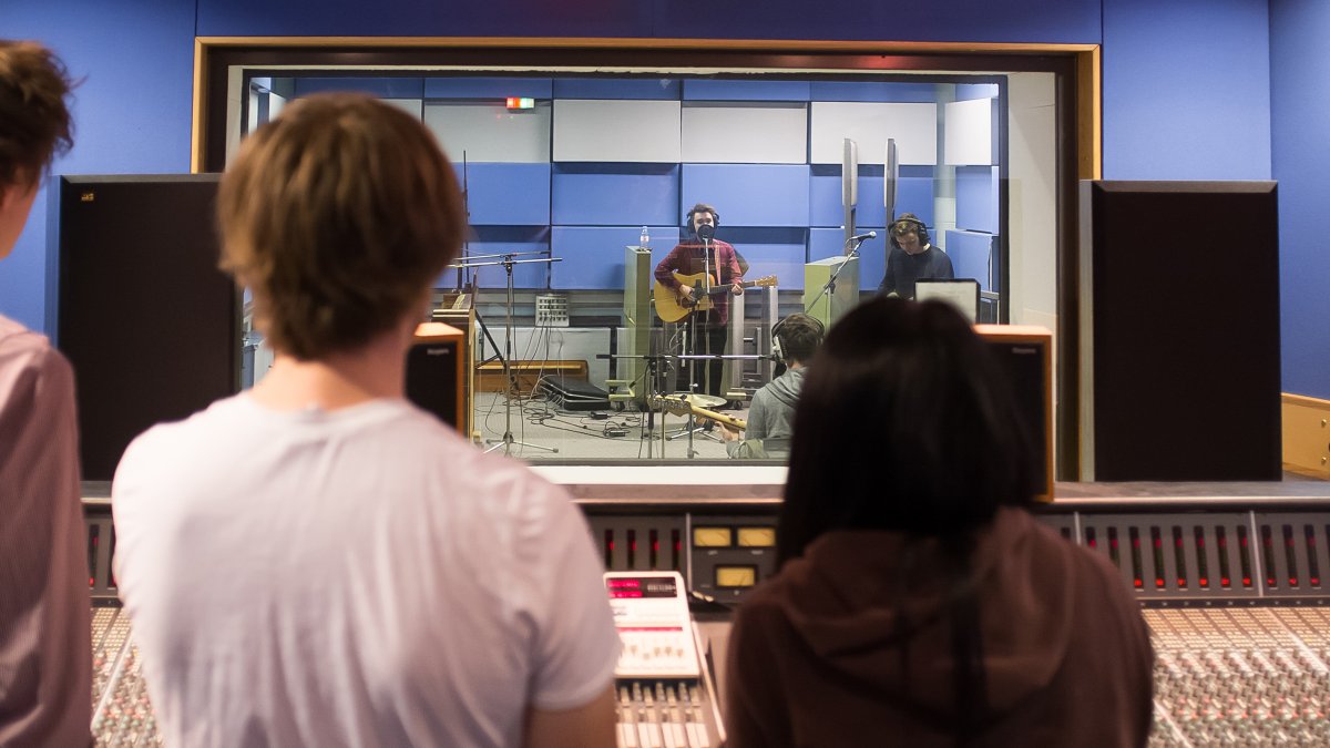 Students looking into studio 2 through glass screen