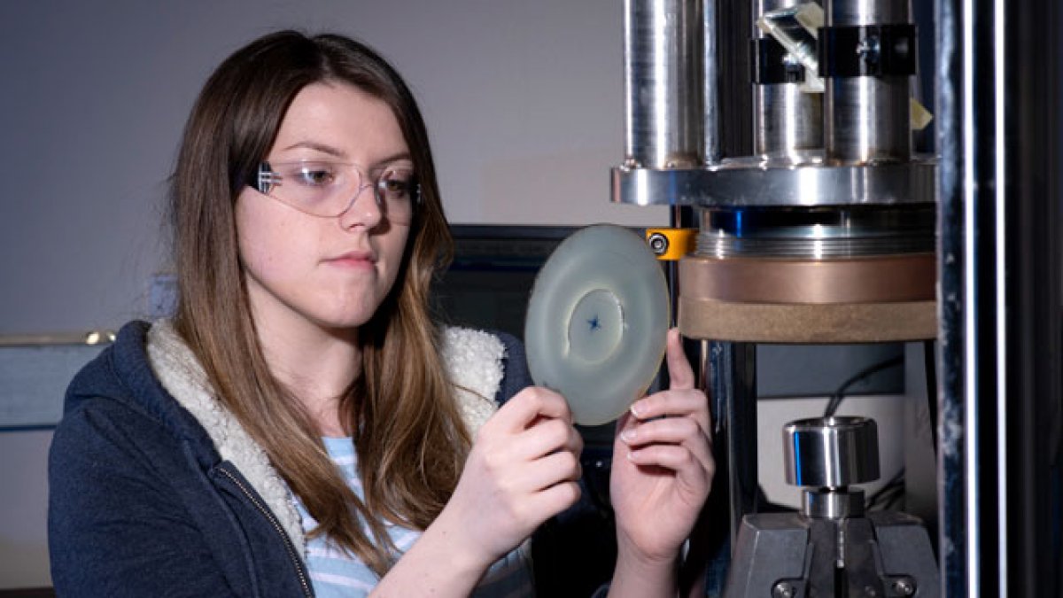 Female student using mechanical engineering equipment