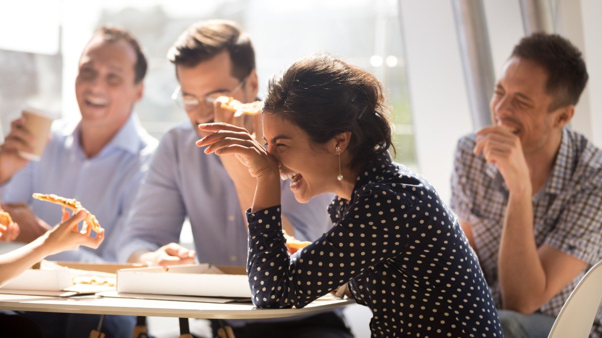 A small group of colleagues seated around a table laugh together