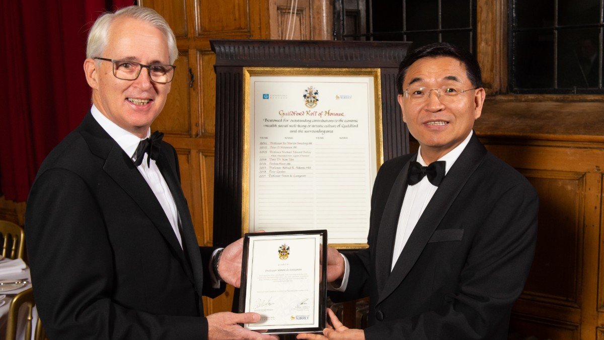 Professor Simon de Lusignan receives a framed certificate from Professor Max Lu