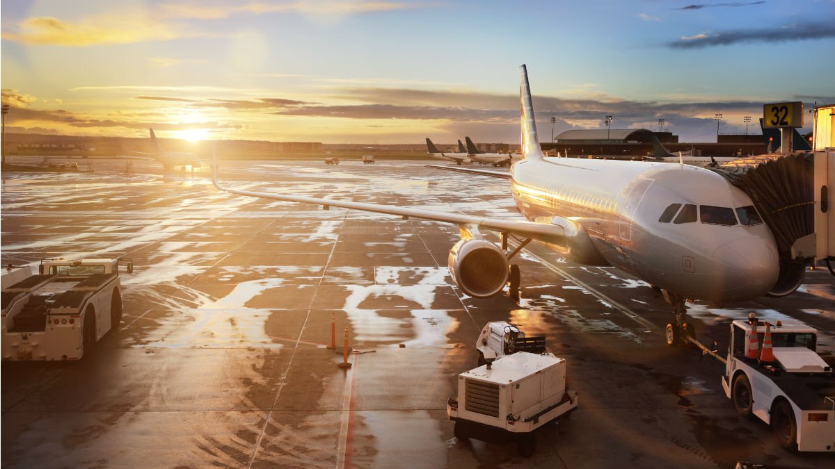 An air plane sits waiting to be refuelled as the sun sets behind it