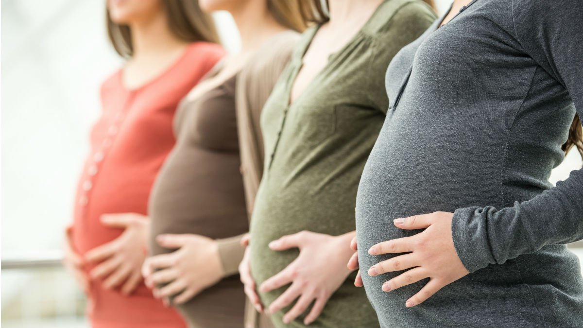 Pregnant women standing in a row holding their bellies
