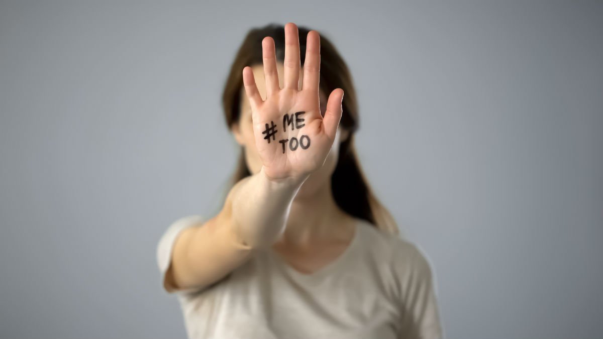 A lady holds her hand to the camera and it has 'Me Too' written on it