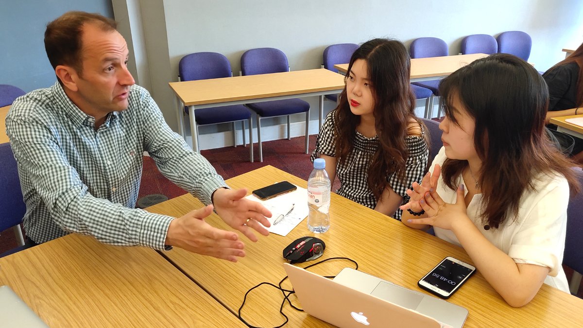 Teacher speaking to two students around table