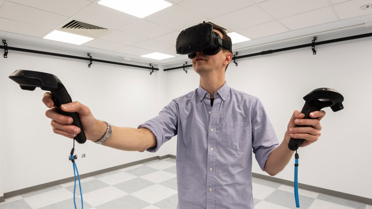 Man wearing a virtual reality headset and holding virtual reality controllers