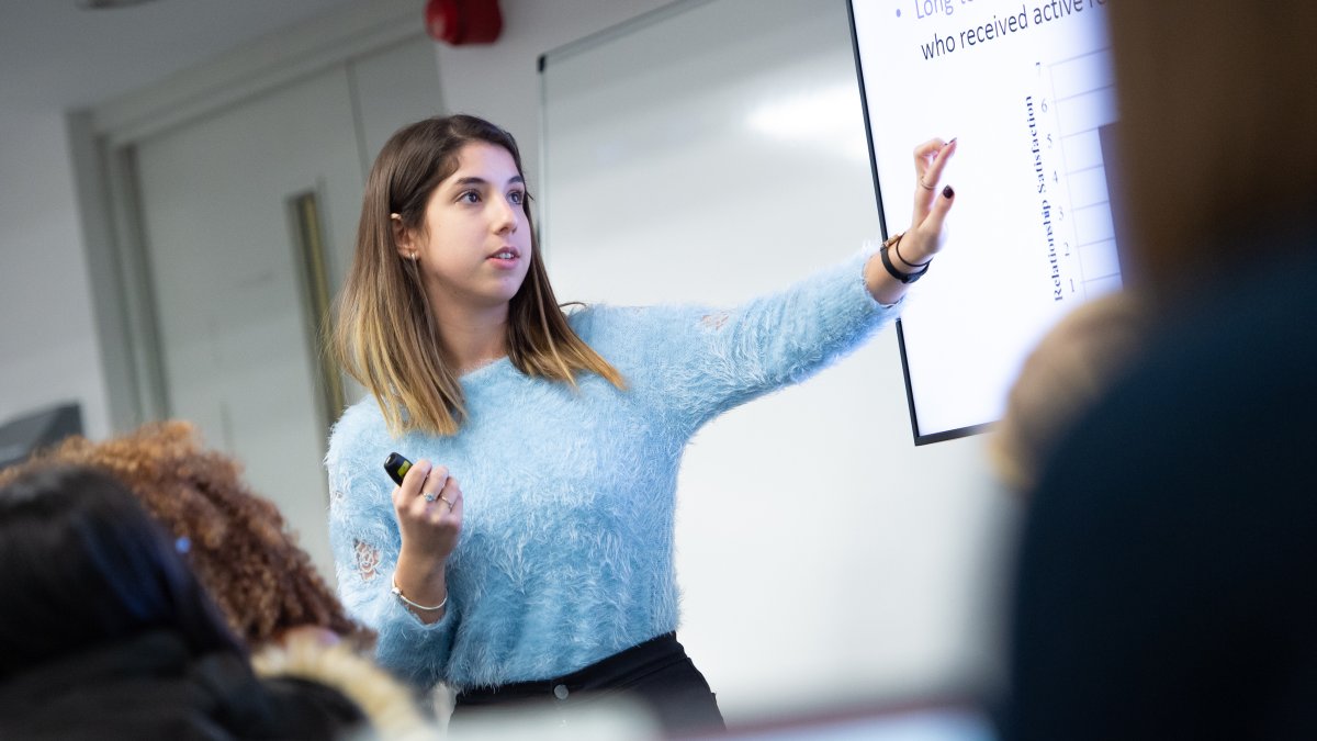 Female student giving presentation in front of whiteboard