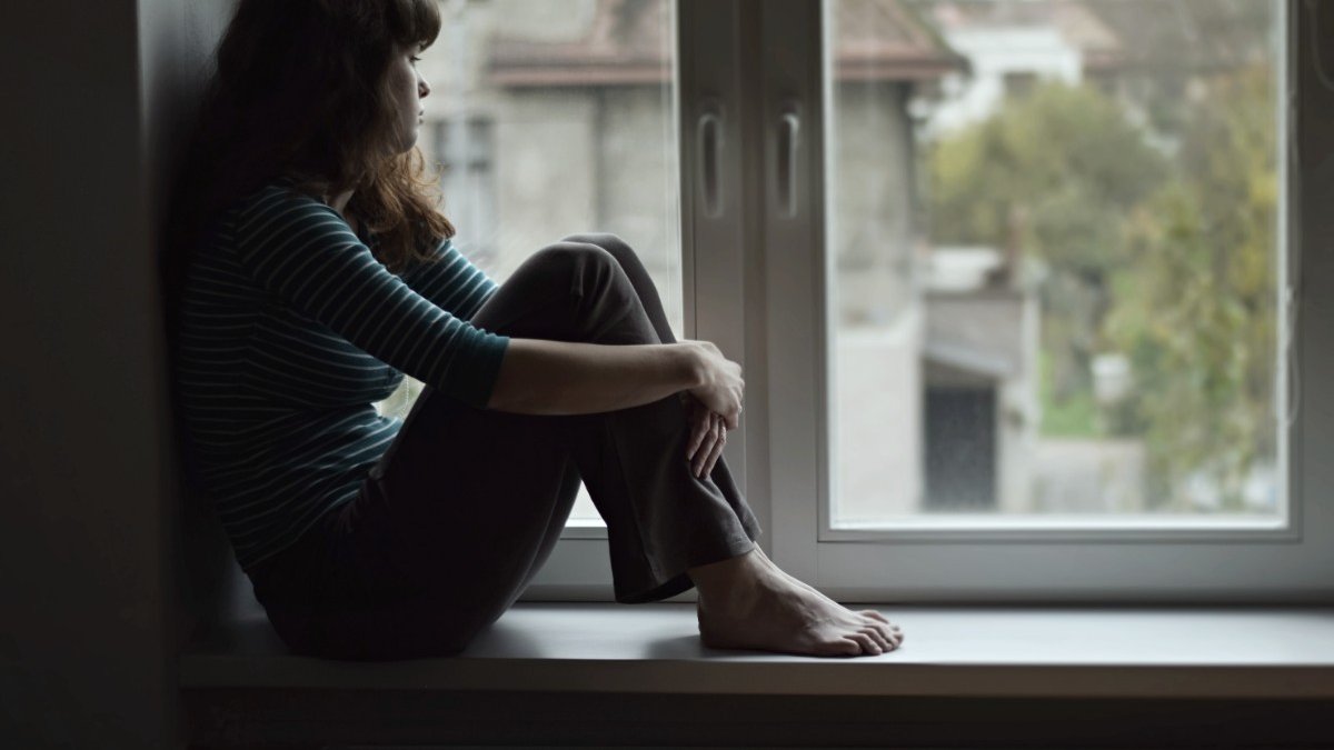 A lady looks outside a window 