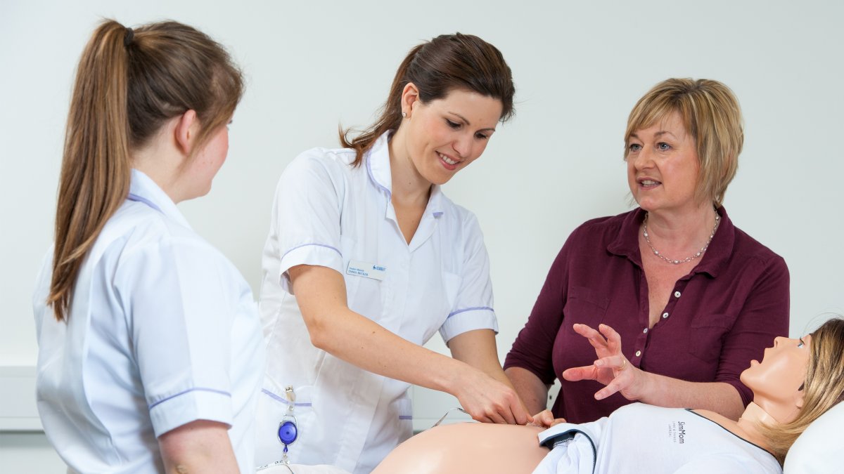 Student midwife checking over pregnant mannequin