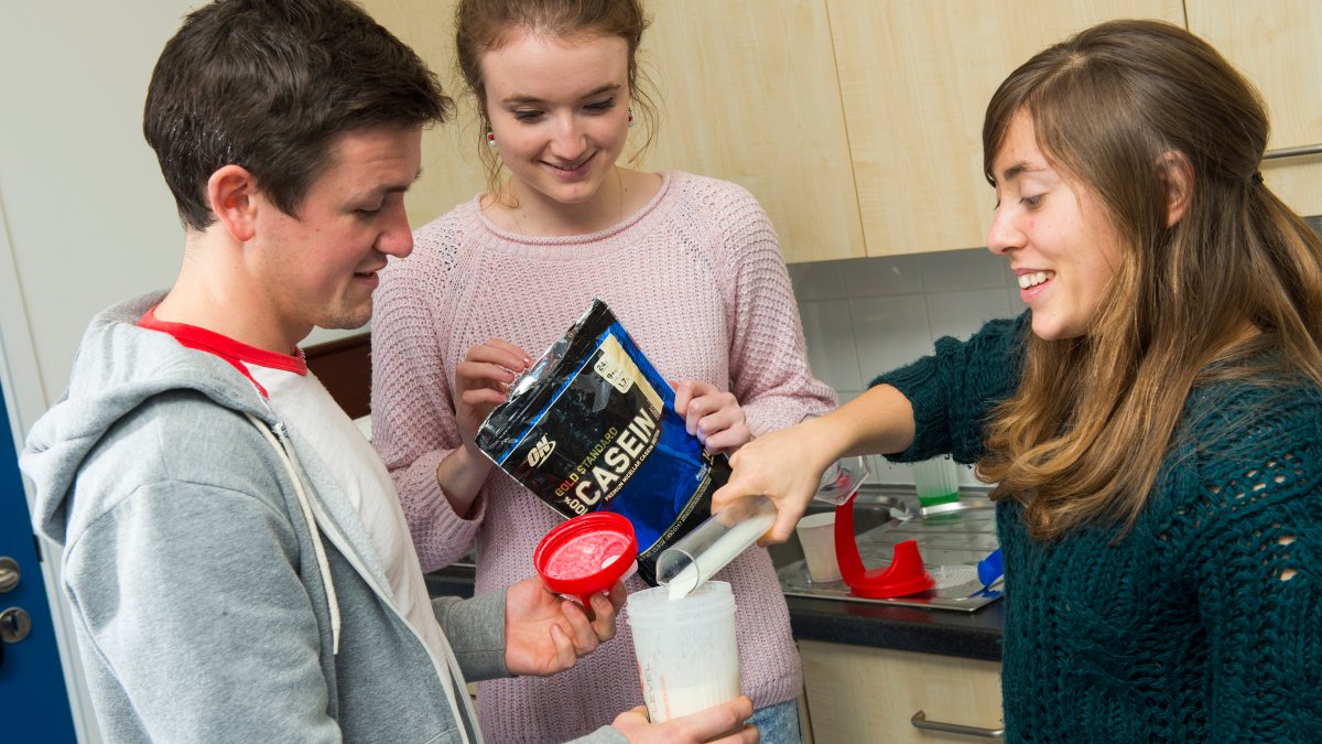 Students pouring casein into a beaker