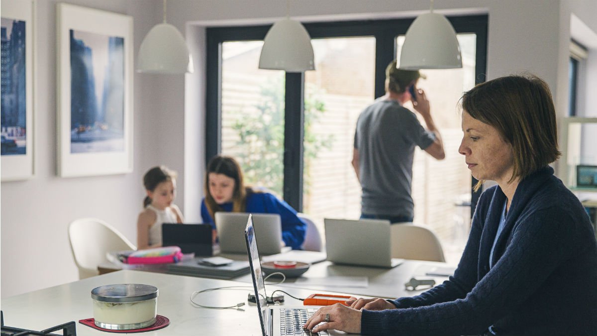 Woman on laptop with family in the background