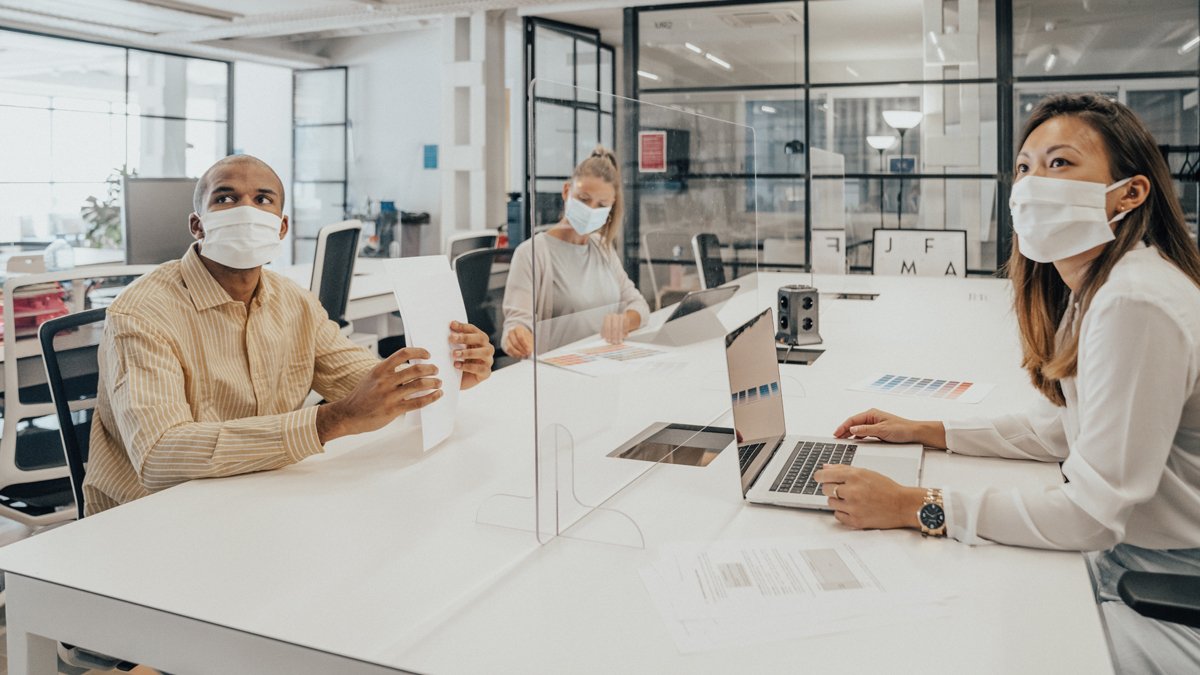 Members of a team in an office, socially distanced and wearing masks.