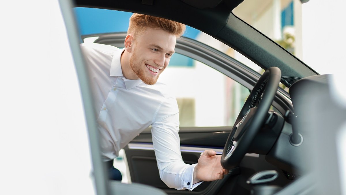 Male student leaning into the driver's seat of a car