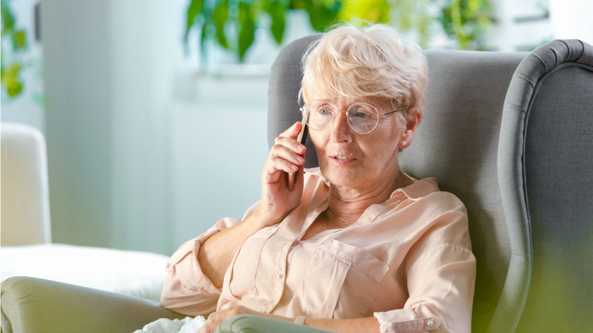 Older woman sat in a chair on the phone