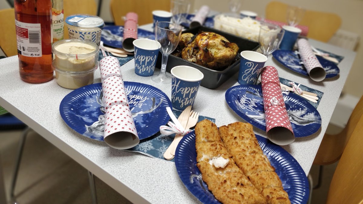 A dinner table with Christmas plates, cups and crackers on